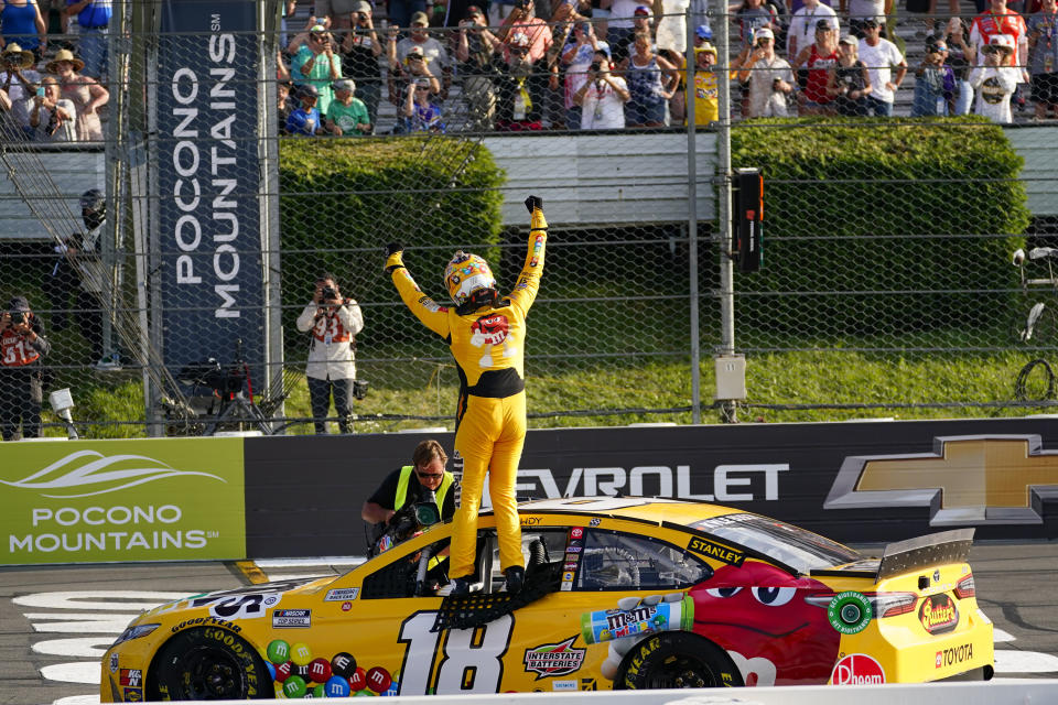 Fans cheer as Kyle Busch stands on the window opening of his race car and celebrates winning a NASCAR Cup Series auto race at Pocono Raceway, Sunday, June 27, 2021, in Long Pond, Pa. (AP Photo/Matt Slocum)