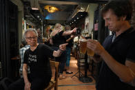 In this Oct. 9, 2020 photo, Grace Ma, left, chats with a customer at her bar Club 71 in Central, a business district of Hong Kong. Nearly 15 years ago, Ma decided to name her bar Club 71, in commemoration of a July 1, 2003 rally where hundreds of thousands of Hong Kongers protested a proposed national security law for the semi-autonomous Chinese city. (AP Photo/Kin Cheung)