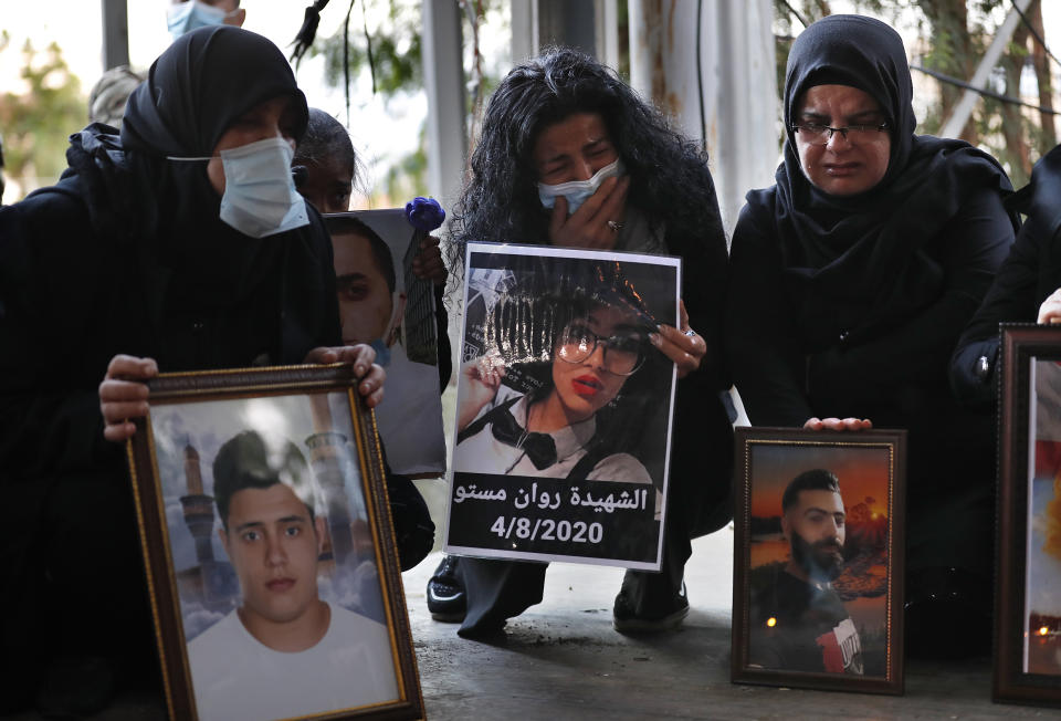 Relatives of victims of the Aug. 4 Beirut port explosion hold portraits of their loved one who killed during the explosion, during a vigil at the seaport main entrance, as they marking four months since the blast that killed more than 200 people and injured thousands, in Beirut, Lebanon Friday, Dec. 4, 2020. An investigation has yet to provide answers or hold any senior official responsible and the victims are demanding answers and justice for their loved ones. (AP Photo/Hussein Malla)