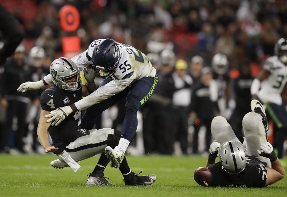 Oakland Raiders quarterback Derek Carr (4) is sacked by Seattle Seahawks defensive end Frank Clark (55) during the second half of an NFL football game at Wembley stadium in London, Sunday, Oct. 14, 2018. (AP Photo/Matt Dunham)