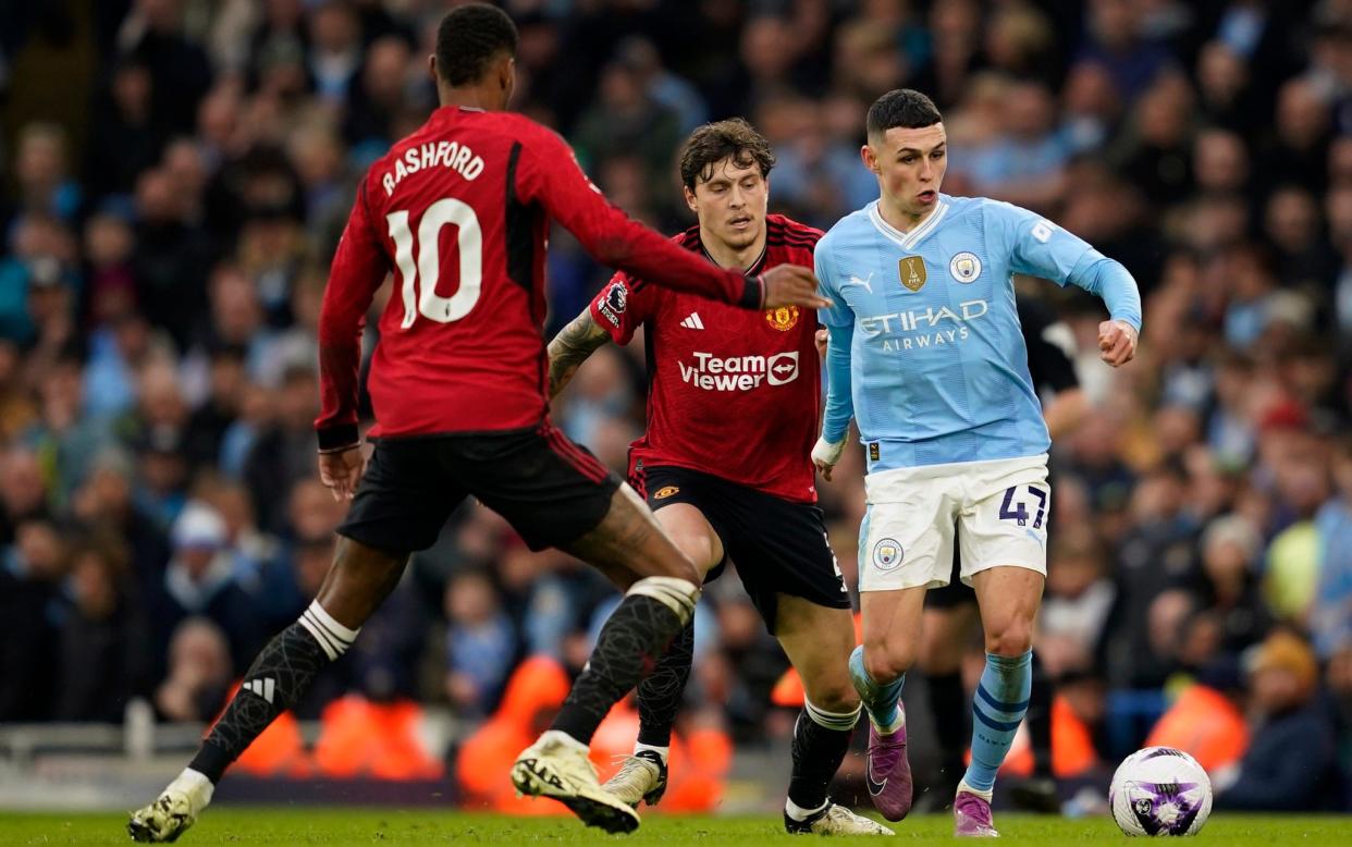 Manchester City's Phil Foden, right, controls the ball the ball as Manchester United's Marcus Rashford, left and Victor Lindelof