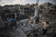 Palestinos revisando sus casas destruidas tras los ataques aéreos de la noche contra la localidad de Beit Hanoun, en el norte de la Franja de Gaza, el viernes 14 de mayo de 2021. (AP Foto/Khalil Hamra)