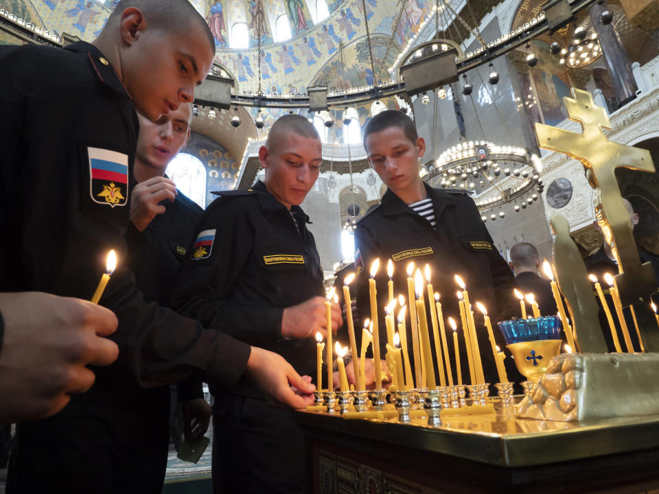 Navy sailors light candles during a religion service to commemorate the crew members that were killed on one of the Russian navy's deep-sea research submersibles at Kronshtadt Navy Cathedral outside St.Petersburg, Russia, Thursday, July 4, 2019. Some crew members survived a fire that killed 14 sailors on one of the Russian navy's deep-sea submersibles, Russia's defense minister said Wednesday without specifying the number of survivors from the blaze. (AP Photo/Dmitri Lovetsky)