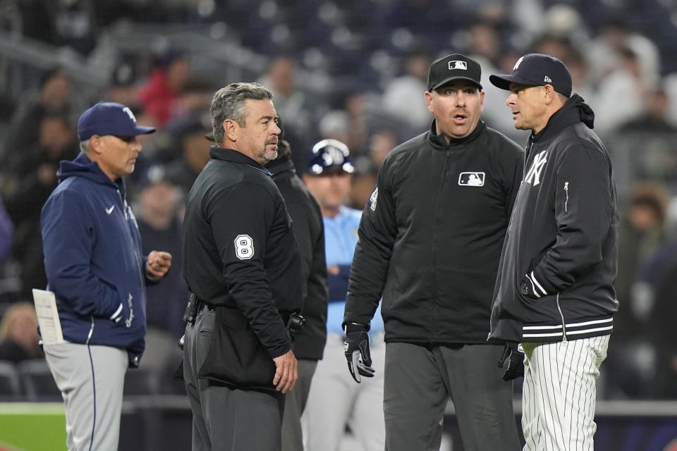 New York Yankees manager Aaron Boone, right, and Tampa Bay Rays manager Kevin Cash, left, talk to officials during the ninth inning of a baseball game Friday, April 19, 2024, in New York. (AP Photo/Frank Franklin II)