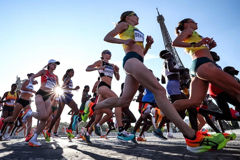 La neozelandesa Camille French y otros atletas pasan por la Torre Eiffel, mientras compiten en el maratón femenino que se realizó el domingo, en el cierre de las competencias