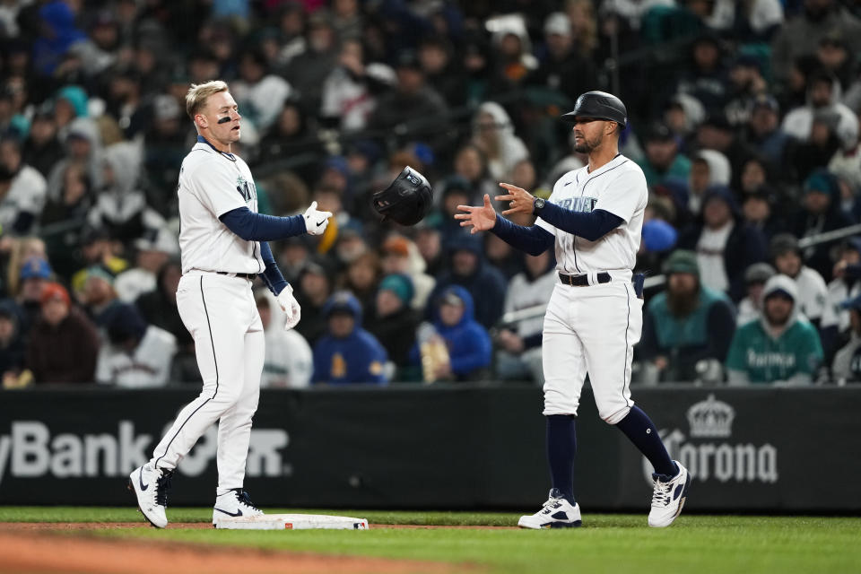 Seattle Mariners' Jarred Kelenic tosses his batting helmet to first base coach Kristopher Negrón after flying out to end the seventh inning against the Cleveland Guardians in a baseball game Saturday, April 1, 2023, in Seattle. (AP Photo/Lindsey Wasson)
