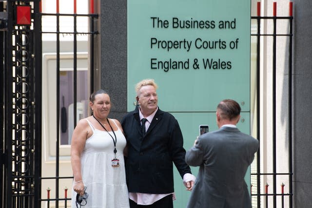 John Lydon, centre, poses for a photo outside the Rolls Building at the High Court 