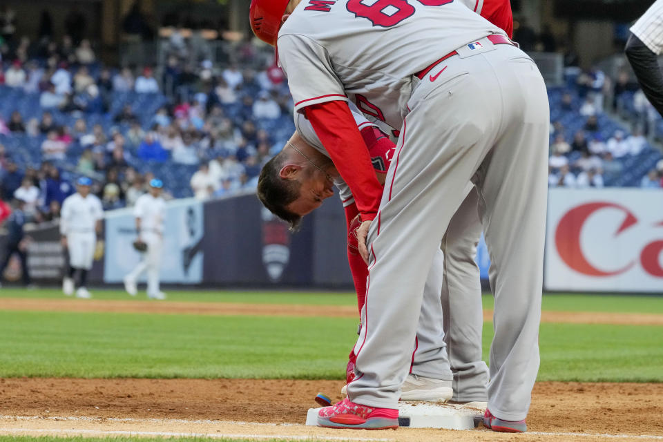 Los Angeles Angels first base coach Damon Mashore (80) checks on Logan O'Hoppe after he was injured during the ninth inning of the team's baseball game against the New York Yankees, Thursday, April 20, 2023, in New York. The Yankees won 9-3. (AP Photo/Mary Altaffer)