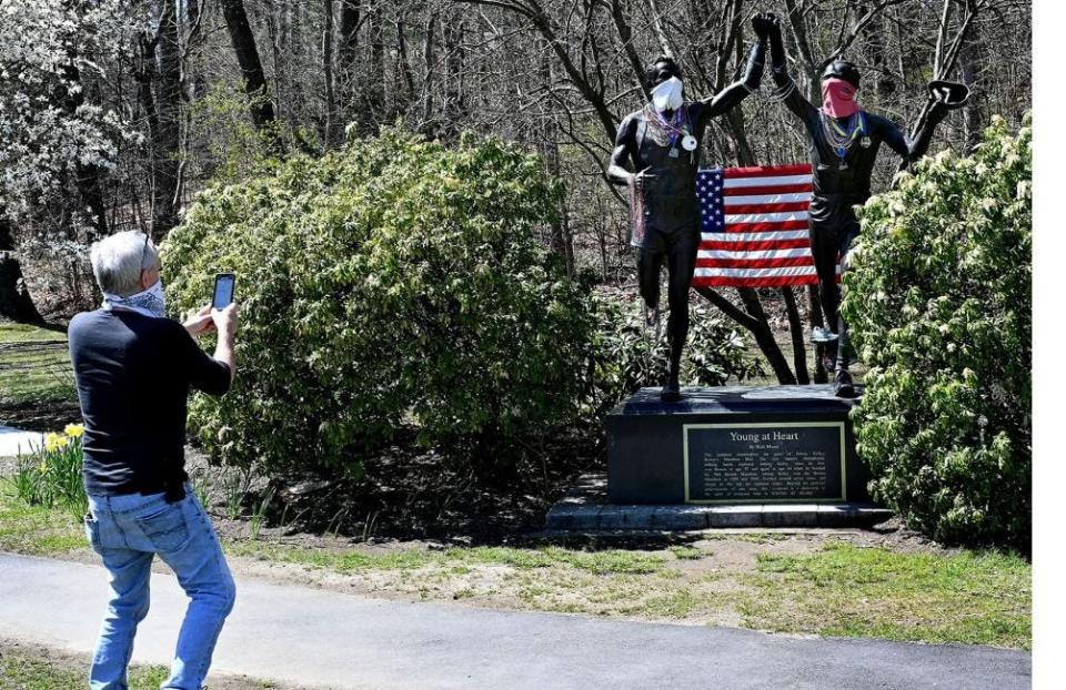 The "Young at Heart" statue in Newton, which shows Boston Marathon legend Johnny Kelley at ages 27 and 84. Kelley ran Boston a record 61 times. Pictured here in 2020, the statue acquired face masks during the COVID-19 pandemic.