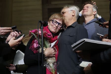 Lee Carter (L) embraces her husband Hollis Johnson while speaking to journalists at the Supreme Court of Canada in Ottawa February 6, 2015. Carter's mother, Kay Carter, traveled to Switzerland to end her life in 2010. REUTERS/Chris Wattie