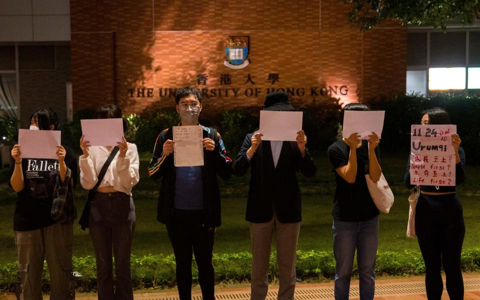 Protesters hold up white paper, some with writings commemorating the deadly Urumqi fire during a gathering at the University of Hong Kong - AP