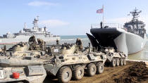 This handout photo taken from a video released on Friday, April 23, 2021 by Russian Defense Ministry Press Service shows, Russian military's armored vehicles roll into landing vessels after drills in Crimea. Russian Defense Minister Sergei Shoigu on Thursday ordered troops back to their permanent bases after a massive military buildup that caused Ukrainian and Western concerns. (Russian Defense Ministry Press Service via AP)