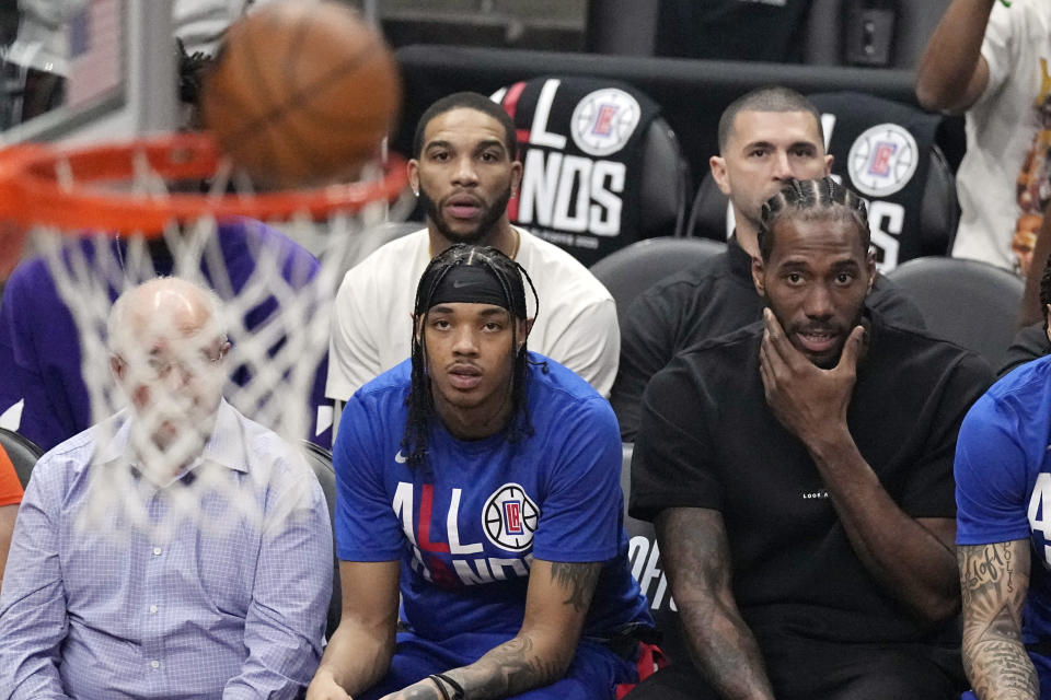 Los Angeles Clippers forward Kawhi Leonard, right, watches from the bench during the first half in Game 4 of a first-round NBA basketball playoff series against the Phoenix Suns Saturday, April 22, 2023, in Los Angeles. (AP Photo/Mark J. Terrill)