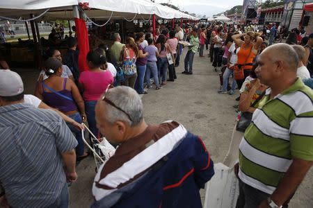People stand in line to buy food at a state-run street market in Caracas November 13, 2014. Picture taken November 13. REUTERS/Carlos Garcia Rawlins