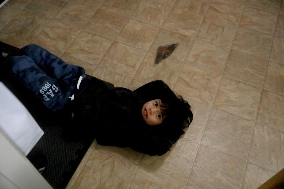 Liam Ponce lies on the linoleum floor in need of repair in the family room