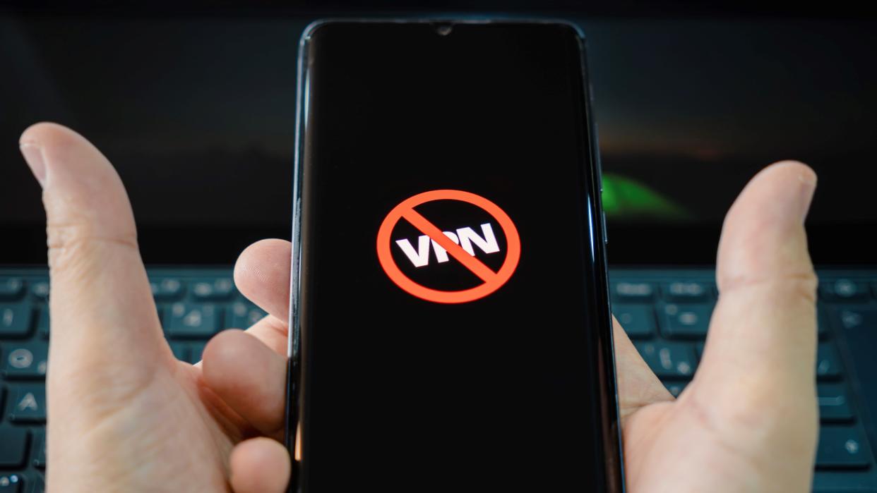  Icon of blocked VPN on a black smartphone screen on a man hands. Blocking VPN services concept . 