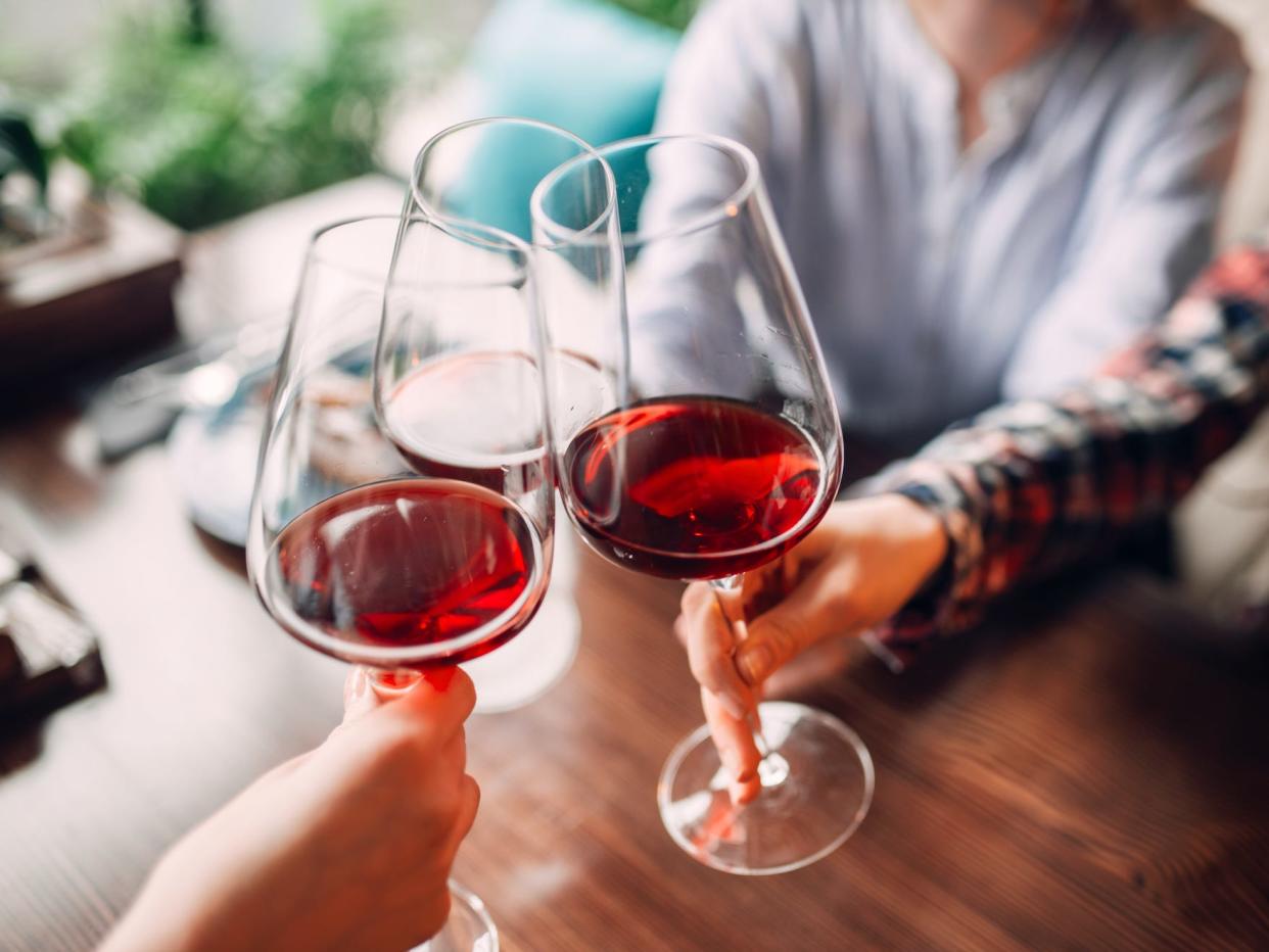 people cheersing glasses of red wine