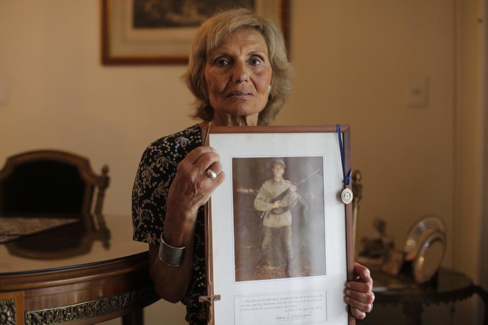 Esta imagen tomada el 13 de febrero de 2017, Dalal Abd sostiene una fotografía de su hijo Marcelo, que murió combatiendo en la guerra de las Malvinas, en su casa en Buenos Aires, Argentina. La familia Abd no está de acuerdo con el plan para poner nombre a los restos de los soldados caídos no identificados enterrados en Malvinas, como su hijo, y lamenta que familias como la suya no fueron consultadas sobre el proceso. Para Abd, si los restos se trasladan a otro lugar "perdemos todo". (AP Foto/Victor R. Caivano)