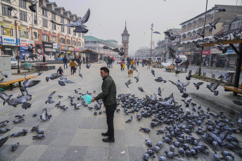 A man feeds pigeons at the main market in Srinagar, Indian controlled Kashmir, Monday, Dec. 11, 2023. India’s top court on Monday upheld a 2019 decision by Prime Minister Narendra Modi’s government to strip disputed Jammu and Kashmir’s special status as a semi-autonomous region with a separate constitution and inherited protections on land and jobs. (AP Photo/Mukhtar Khan)