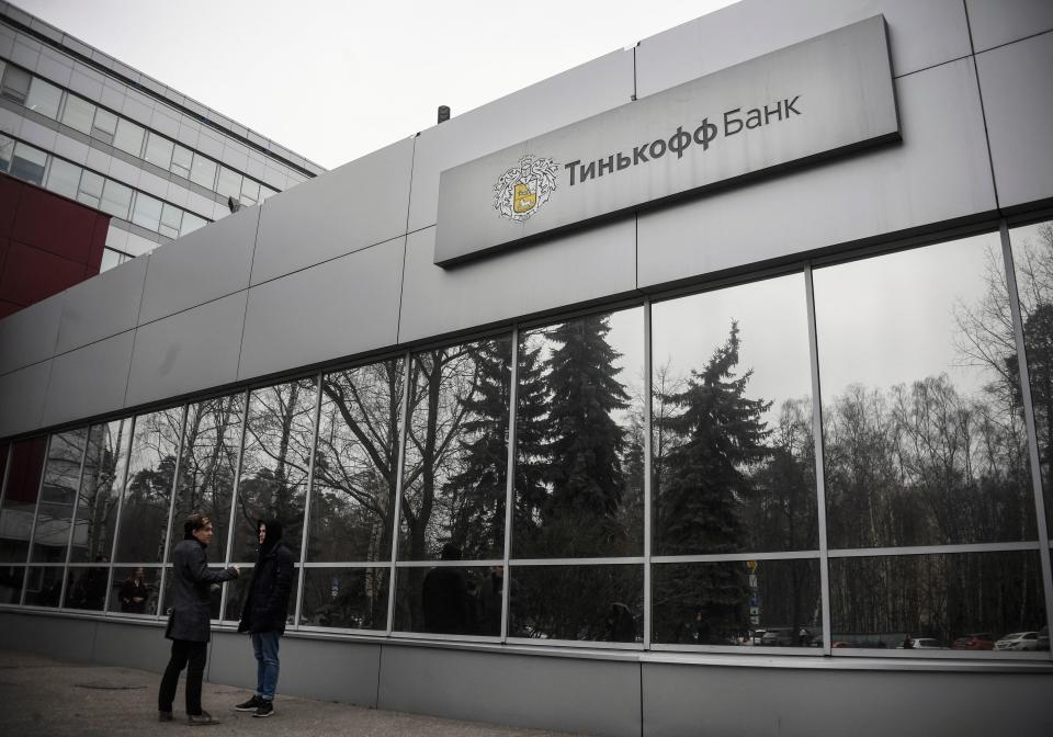 People walk past the logo of the Tinkoff Bank headquarters in Moscow on March 6, 2020. - The shares of the Russian private Tinkoff Bank, a pioneer of online banking technology, collapsed on the stock market on March 6, 2020, after Oleg Tinkov the president and founder of the TCS Group, the parent company of Tinkoff Bank, was charged with filing false tax returns, according to the U.S. Department of Justice. (Photo by Alexander NEMENOV / AFP) (Photo by ALEXANDER NEMENOV/AFP via Getty Images)