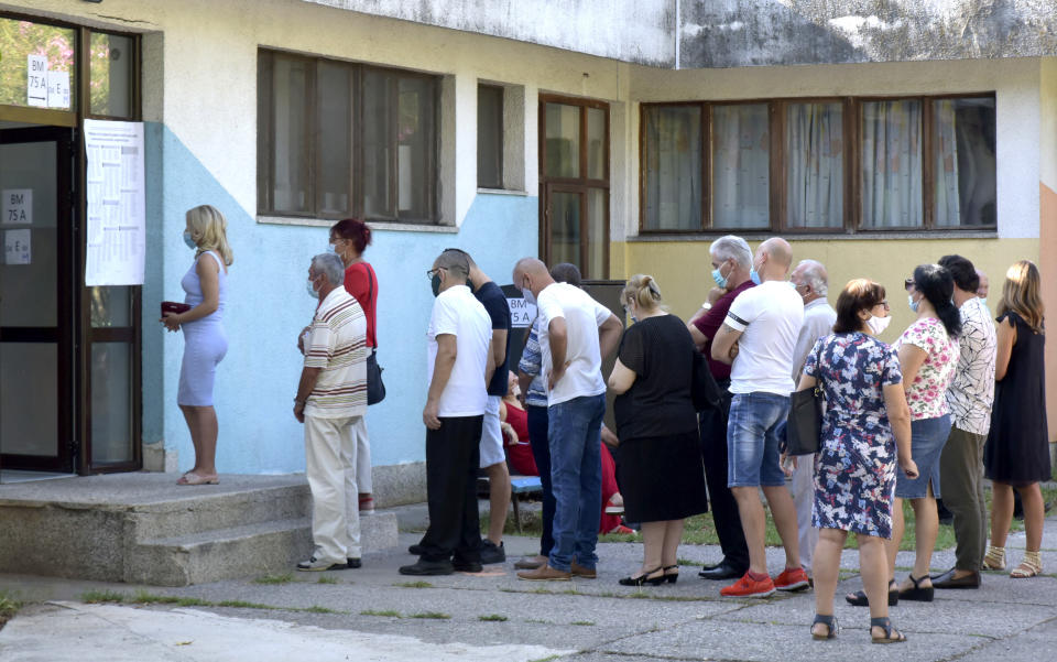 People wait in line at a poling station in Podgorica, Montenegro, Sunday, Aug. 30, 2020. Voters in Montenegro on Sunday cast ballots in a tense election that is pitting the long-ruling pro-Western party against the opposition seeking closer ties with Serbia and Russia. The parliamentary vote is marked by a dispute over a law on religious rights that is staunchly opposed by the influential Serbian Orthodox Church. (AP Photo/Risto Bozovic)