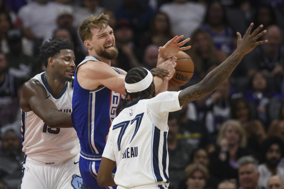 Memphis Grizzlies forward Jaren Jackson Jr., left, and guard DeJon Jarreau, right, battle for a rebound with Sacramento Kings forward Domantas Sabonis, center, during the first half of an NBA basketball game in Sacramento, Calif., Monday, March 18, 2024. (AP Photo/Randall Benton)