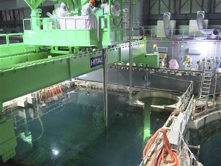 Workers wearing protective suits and masks carry out an operation to remove fuel rods from a spent fuel pool inside the No.4 reactor building at Tokyo Electric Power Co's (TEPCO) Fukushima Daiichi nuclear power plant in Fukushima prefecture November 18, 2013, in this handout photograph taken and released by TEPCO. REUTERS/Tokyo Electric Power Co/Handout via Reuters