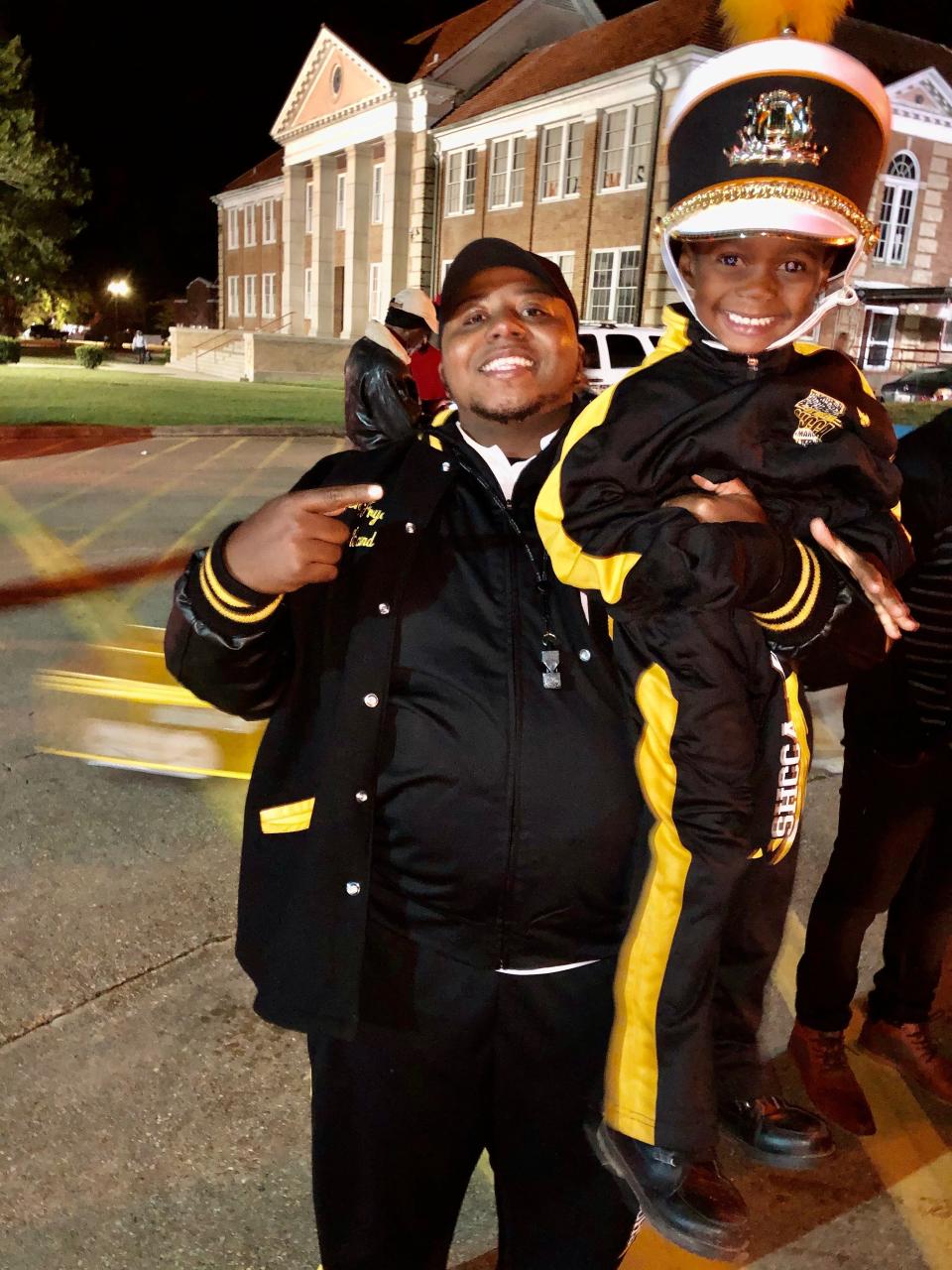 Chesteron Frye, director of bands for the St. Helena College and Career Academy in Greensburg, La., holds up a smiling Jeremiah Travis after a band performance.