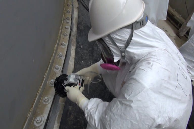 Image taken by TEPCO on September 4, 2013 shows a worker checking radiation levels at a water tank at the Fukushima nuclear power plant. Vapour has begun rising again from a reactor at the plant, more than two-and-a-half years after its core melted down, TEPCO said Friday