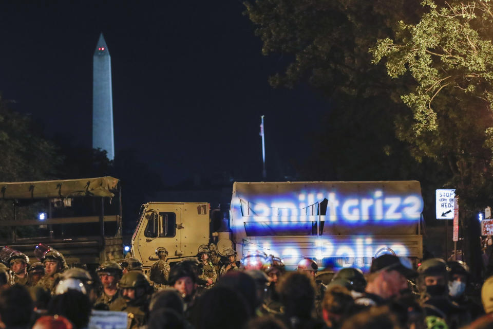 Los manifestantes proyectan las palabras "desmilitaricemos a la policía" en un vehículo militar durante protestas por la muerte de George Floyd, la noche del miércoles 3 de junio de 2020, cerca de la Casa Blanca, en Washington. Floyd, un hombre negro, murió después de ser retenido por policías de Minneapolis. (AP Foto/Alex Brandon)