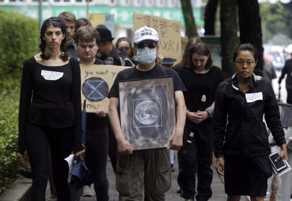 FILE - In this Saturday, Sept. 21, 2019 file photo, protesters march with a picture of a "dead earth" during a global climate strike named ''Earth Funeral'' in Taipei, Taiwan. Many young climate activists say they feel hopeless and overwhelmed _ and psychologists say that’s OK and it’s good they’re talking about it. It’s sometimes called climate change anxiety and you don’t have to be an activist or young to feel it. (AP Photo/Chiang Ying-ying)