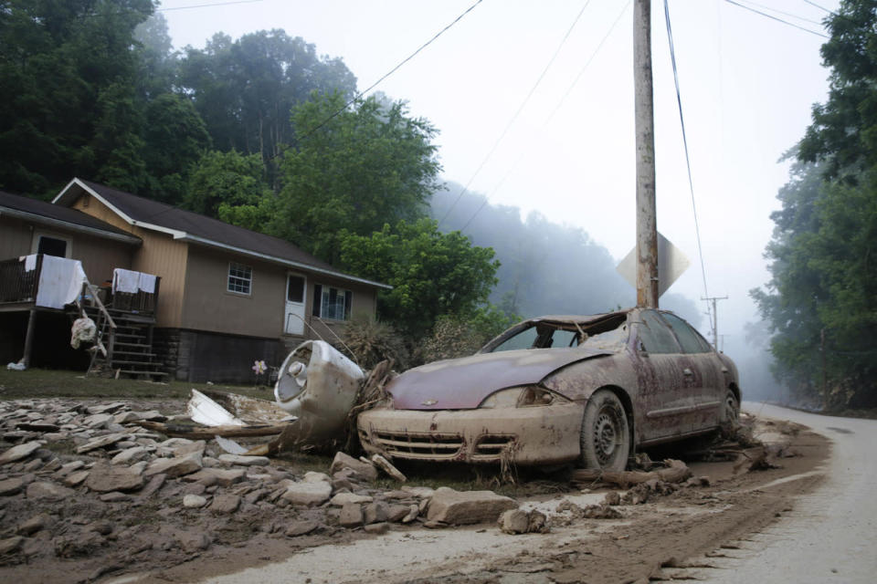 A destroyed car rests in front of a house after flooding