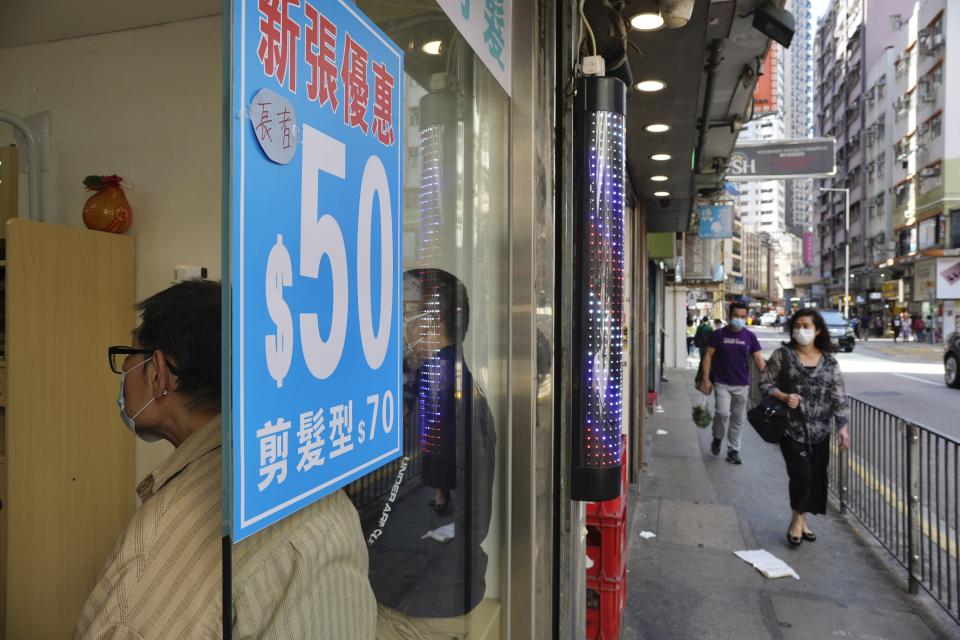 People wearing face masks wait to get haircut at a salon after temporarily closing in Hong Kong, Thursday, March 10, 2022. (AP Photo/Vincent Yu)