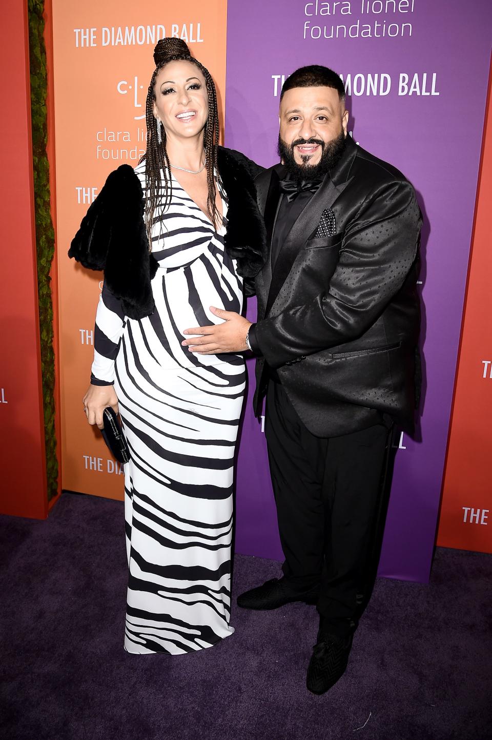 Nicole Tuck in a zebra print floor-length gown standing taller than DJ Khaled in a dark suit.