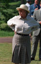 <p>Another photo of the Queen at the Windsor Horse Show shows her wearing her favoured attire. A straw hat, baggy shirt and a pleated checked midi skirt. <i>[Photo: Rex]</i></p>