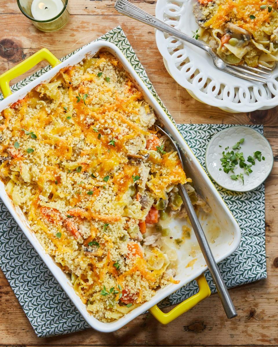 ground chicken noodle casserole in a white rectangle baking dish with a portion scooped out on a white plate next to it