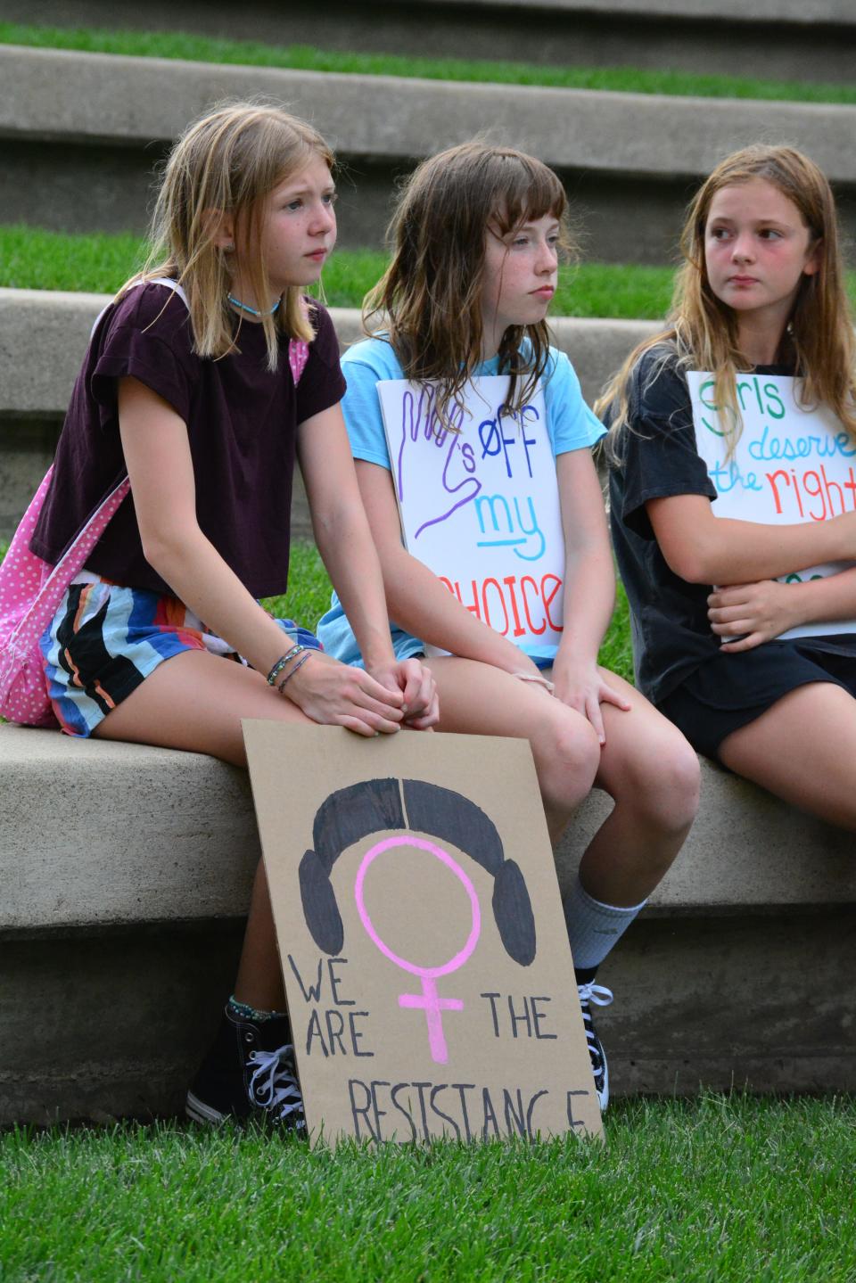 Ivy Blakey, 13, Brooklyn Alexander, 12, and Darcy Chegwidden, 12, listen to speakers and hold protest signs Saturday during an abortion rights rally outside of the Boone County Courthouse.