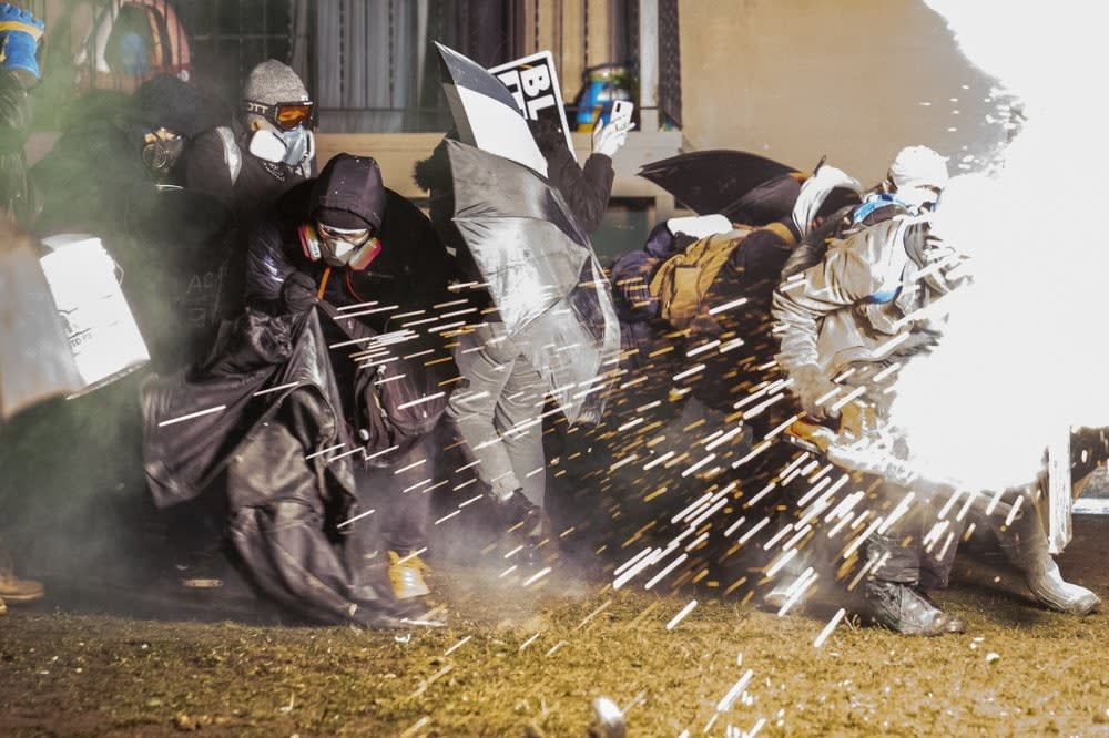 Demonstrators take cover from crowd-dispersal munitions from police outside the Brooklyn Center Police Department while protesting the shooting death of Daunte Wright, late Tuesday, April 13, 2021, in Brooklyn Center, Minn. (AP Photo/John Minchillo)