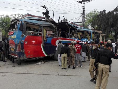 Policemen and rescue officials walk near a bus damaged in a bomb blast in Peshawar, Pakistan March 16, 2016. REUTERS/Fayaz Aziz