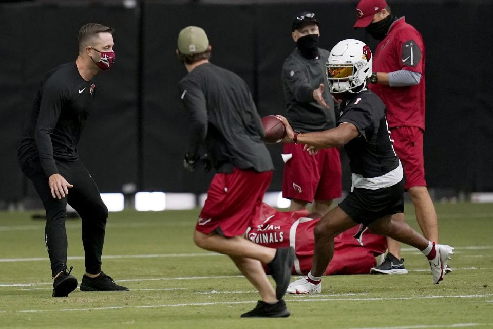 Arizona Cardinals quarterback Kyler Murray (1) tosses the ball to a coach as head coach Kliff Kingsbury, left, looks on as the quarterbacks run drills during an NFL football workout Wednesday, Aug. 12, 2020, in Glendale, Ariz. (AP Photo/Ross D. Franklin)