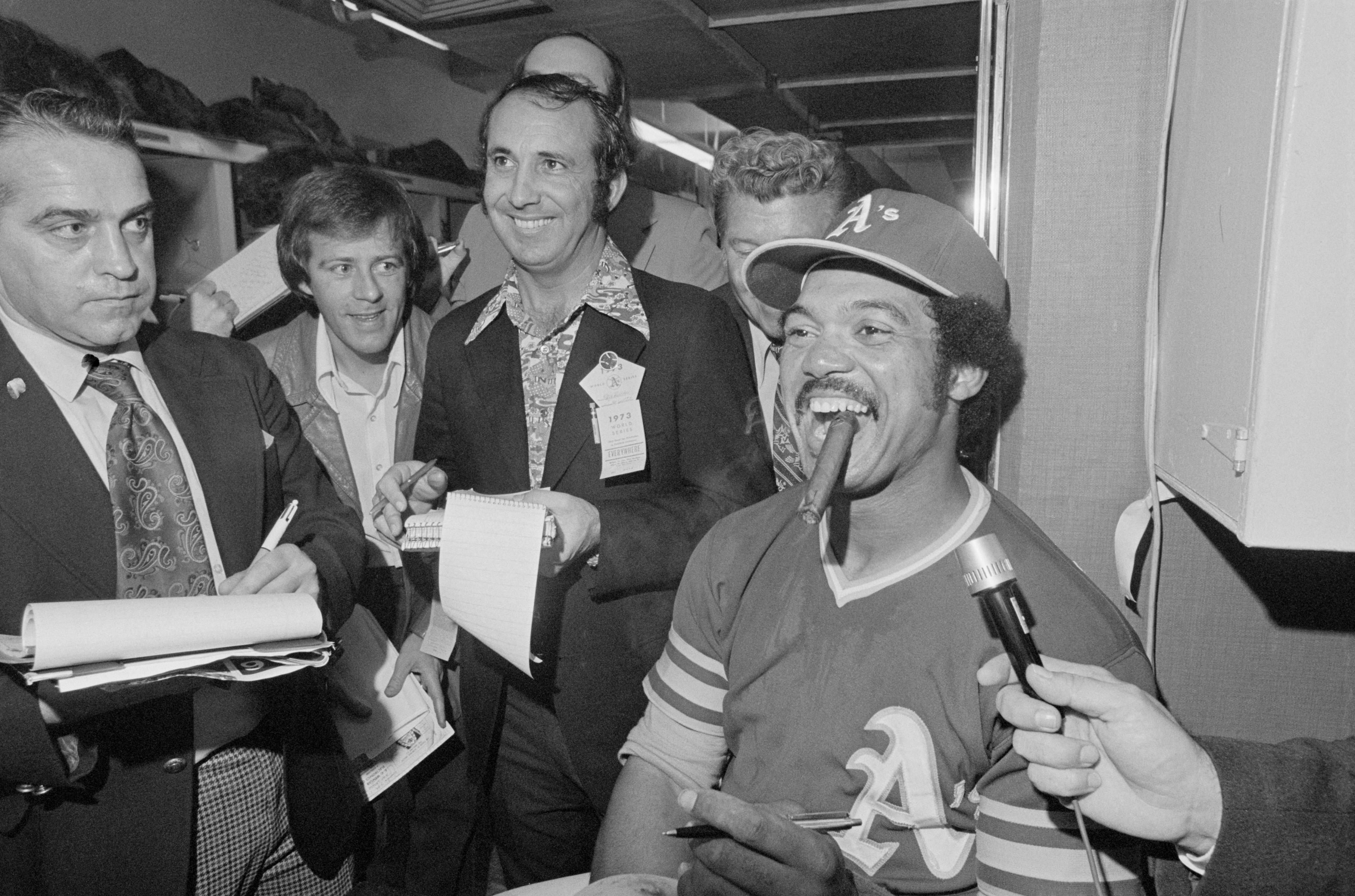 (Original Caption) Oakland, Calif.: The Most Valuable Player of the 1973 World Series, Oakland A's outfielder Reggie Jackson, smokes a victory cigar after the A's won their second consecutive World Championship by batting the New York Mets 5-2 in the seventh inning of the Series. Jackson said after the last game that his life had been threatened before the American League Playoffs and that he has had two FBI men with him since.