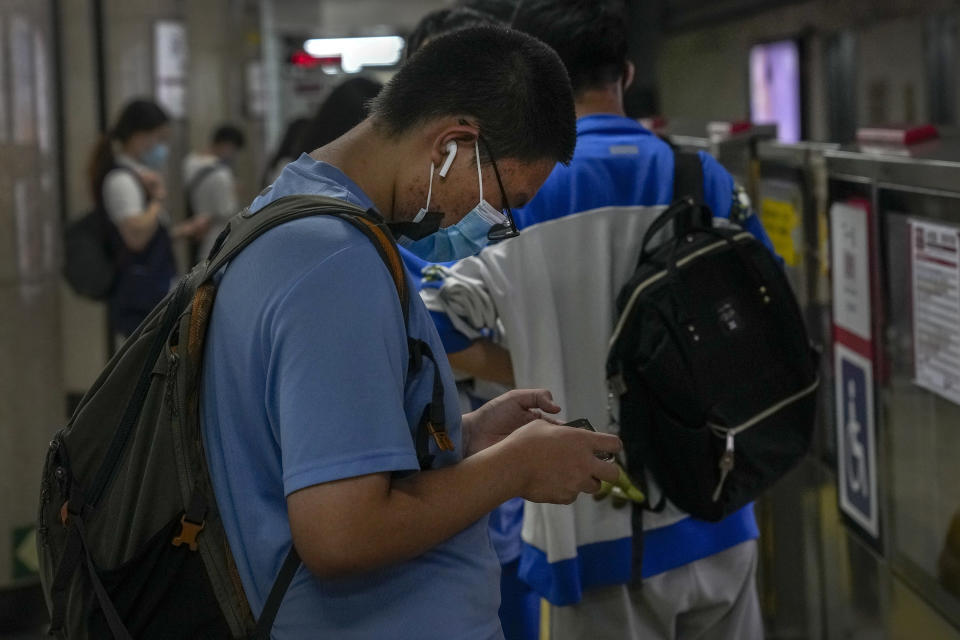 A student plays an online game on his smartphone as he waits for his train at a subway station in Beijing Tuesday, Sept. 14, 2021. China has set new rules limiting the amount of time kids can spend playing online games. (AP Photo/Andy Wong)