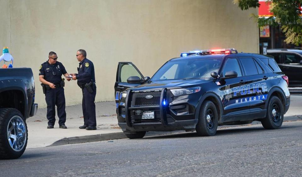 A pair of Mendota police officers huddle during a traffic stop on Thursday, Aug. 17, 2023.