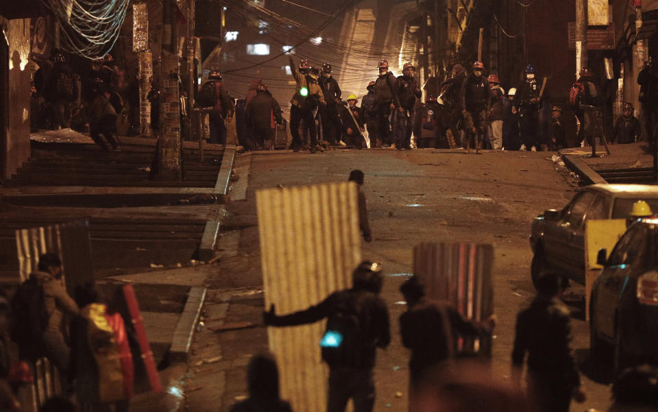 Los mineros, partidarios del presidente Evo Morales, se enfrentan con estudiantes universitarios usando escudos improvisados durante una protesta contra el mandatario en La Paz, Bolivia, el miércoles 6 de noviembre de 2019. (AP Foto / Juan Karita)