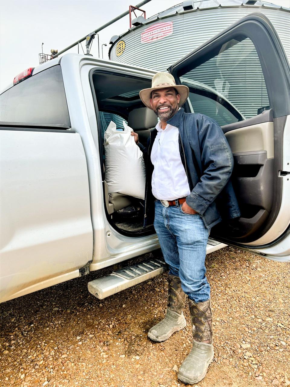 PJ Haynie with a bag of rice near one of his grain silos in Arkansas. The Arkansas Delta's conditions are perfect for growing rice.