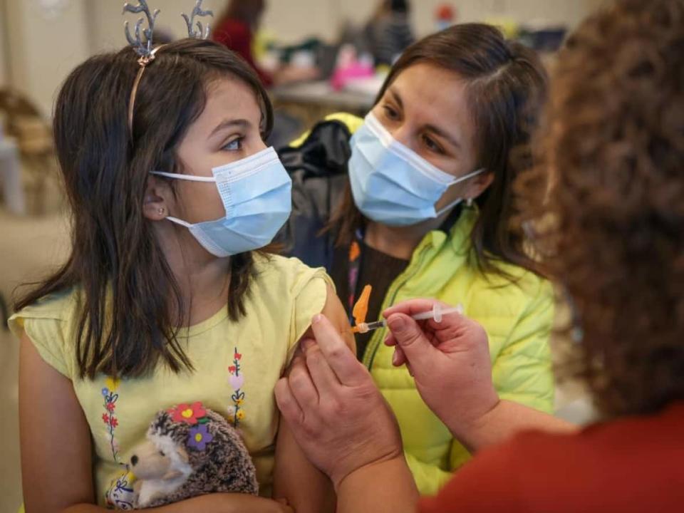 Sofia Flores Rojas, 9, is comforted by her mom Alejandra as she receives a COVID-19 vaccine in Calgary last November. (Leah Hennel/AHS - image credit)