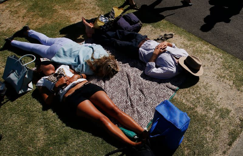 Tennis spectators rest on the grass on the first day of the Australian Open tennis tournament in Melbourne