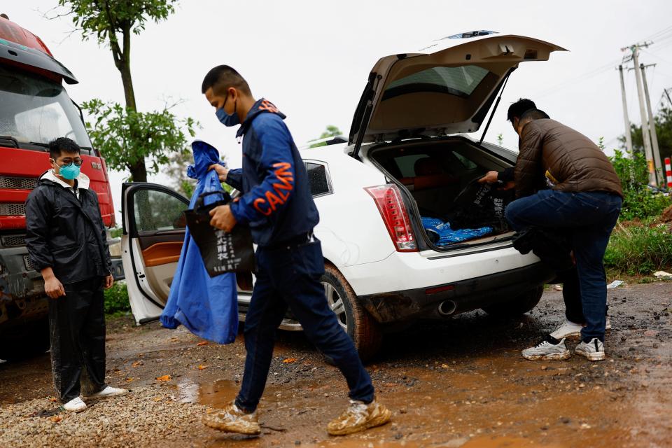 Relatives of victims take rain covers from a car near the entrance of  Lu village near the plane crash site (REUTERS)