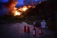 People watch before they leave as advancing fires rage Hisaronu area, Turkey, Monday, Aug. 2, 2021. For the sixth straight day, Turkish firefighters battled Monday to control the blazes that are tearing through forests near Turkey's beach destinations. Fed by strong winds and scorching temperatures, the fires that began Wednesday have left eight people dead. Residents and tourists have fled vacation resorts in flotillas of small boats or convoys of cars and trucks. (AP Photo)