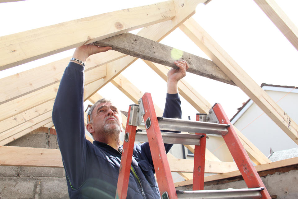 Man measures timber for roof